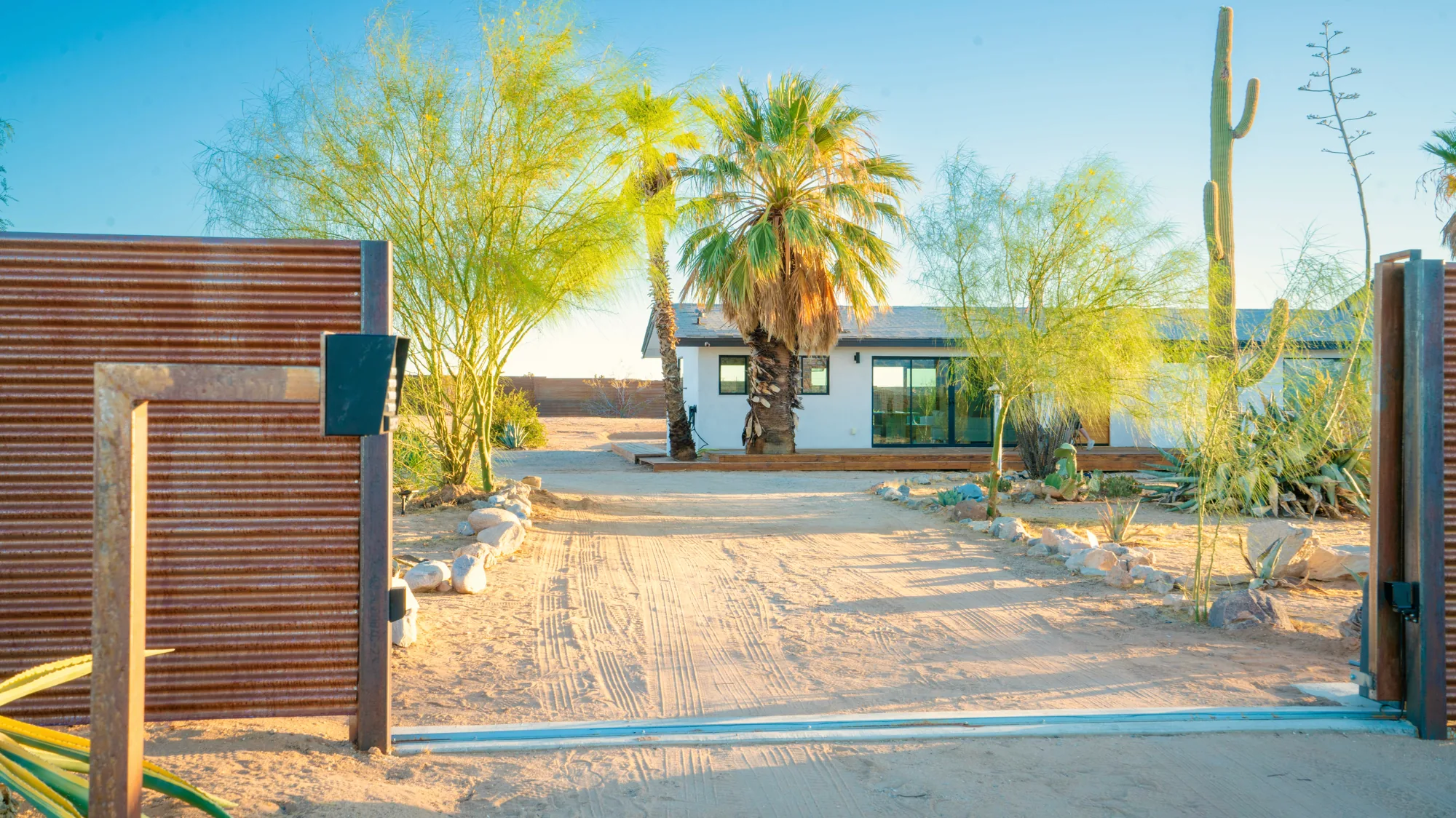 Electric entry gate open to the private drive, house and palms beyond