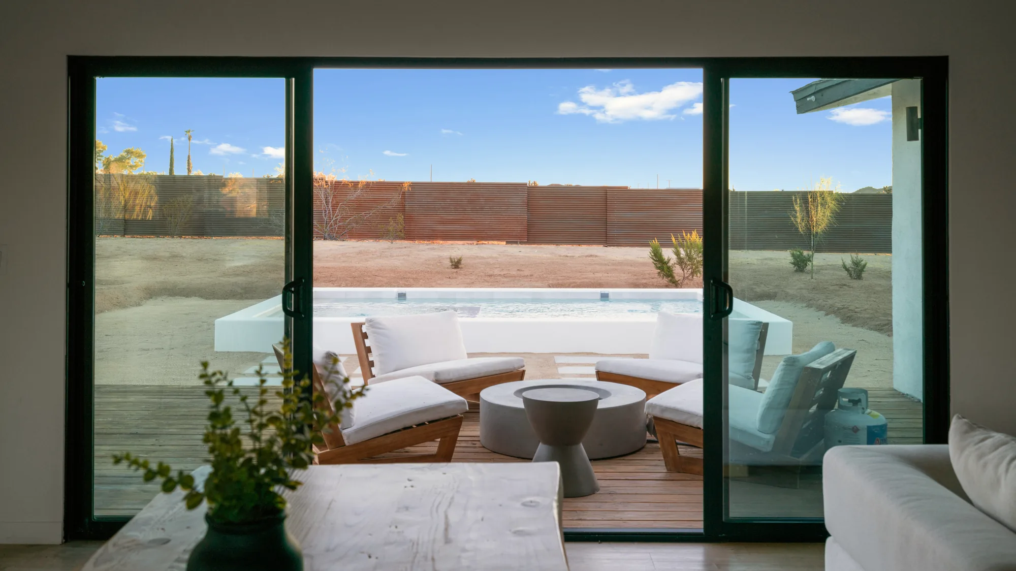 Living room sliding doors open to the pool deck and desert beyond