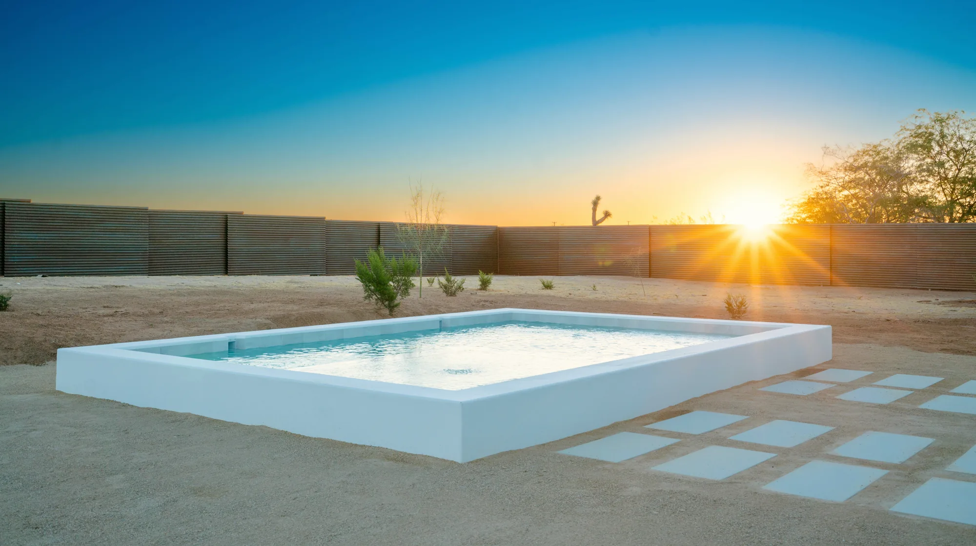 SaguaroHaus — private pool at sunset, sun breaking over the corrugated steel fence