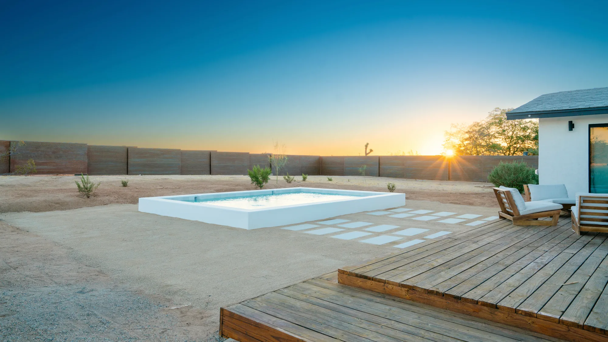 Pool and teak deck at sunset, loungers facing the open desert