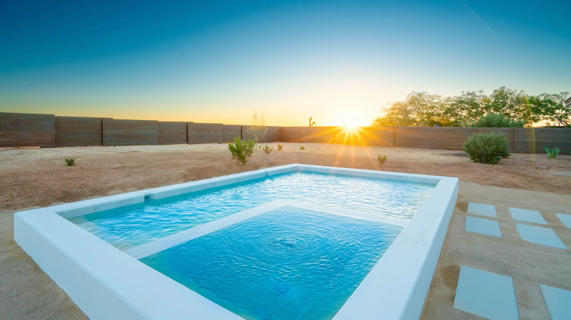 Private pool at golden hour, sun breaking over the desert horizon