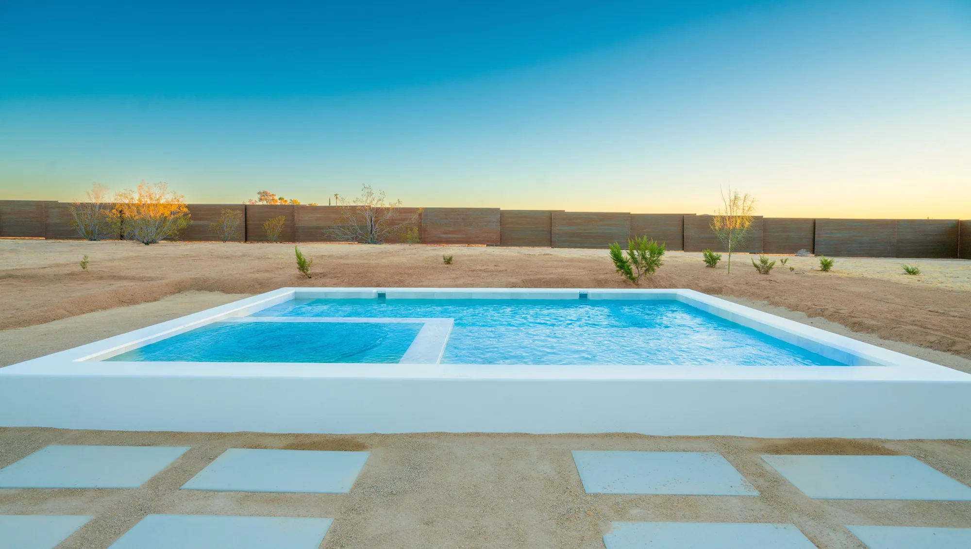 Baja lounge shelf and pool at dusk against the steel perimeter fence