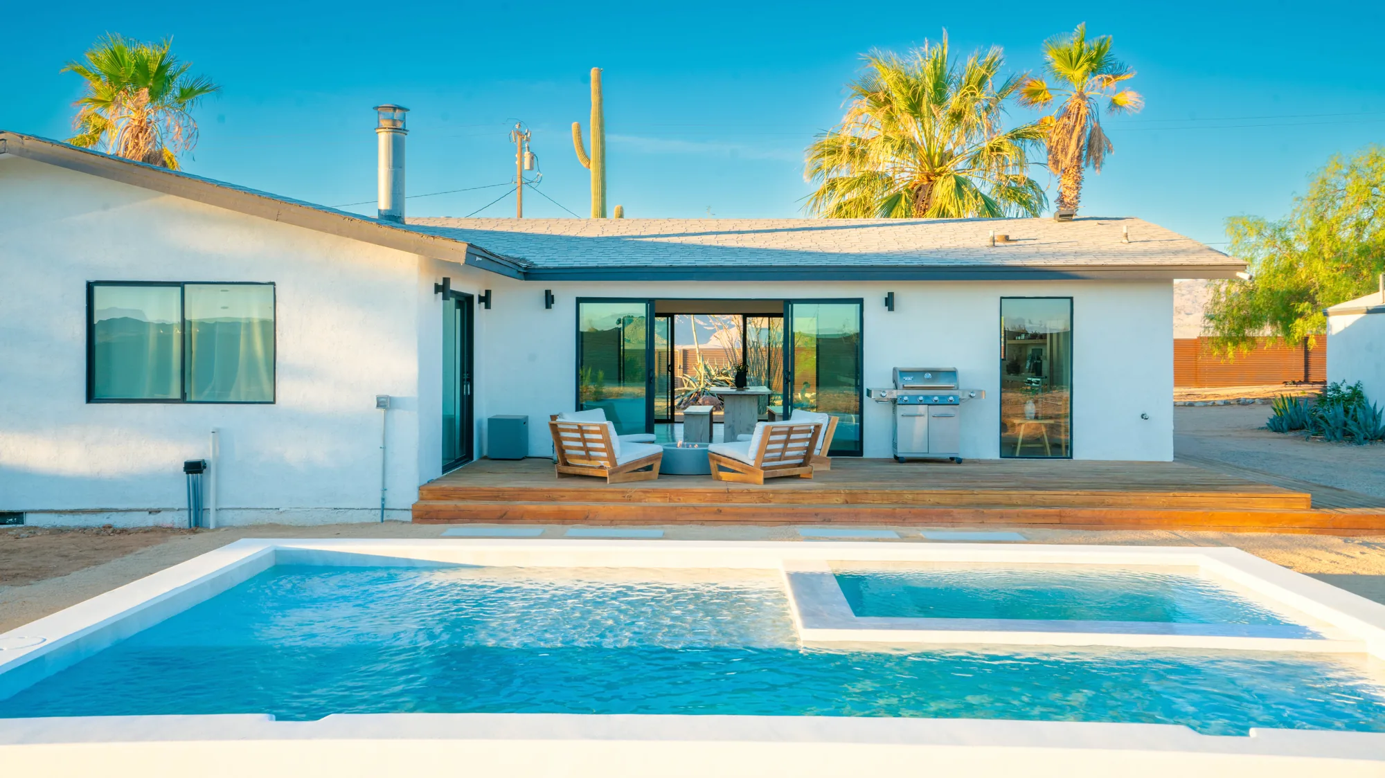 Pool with integrated spa, deck and house beyond