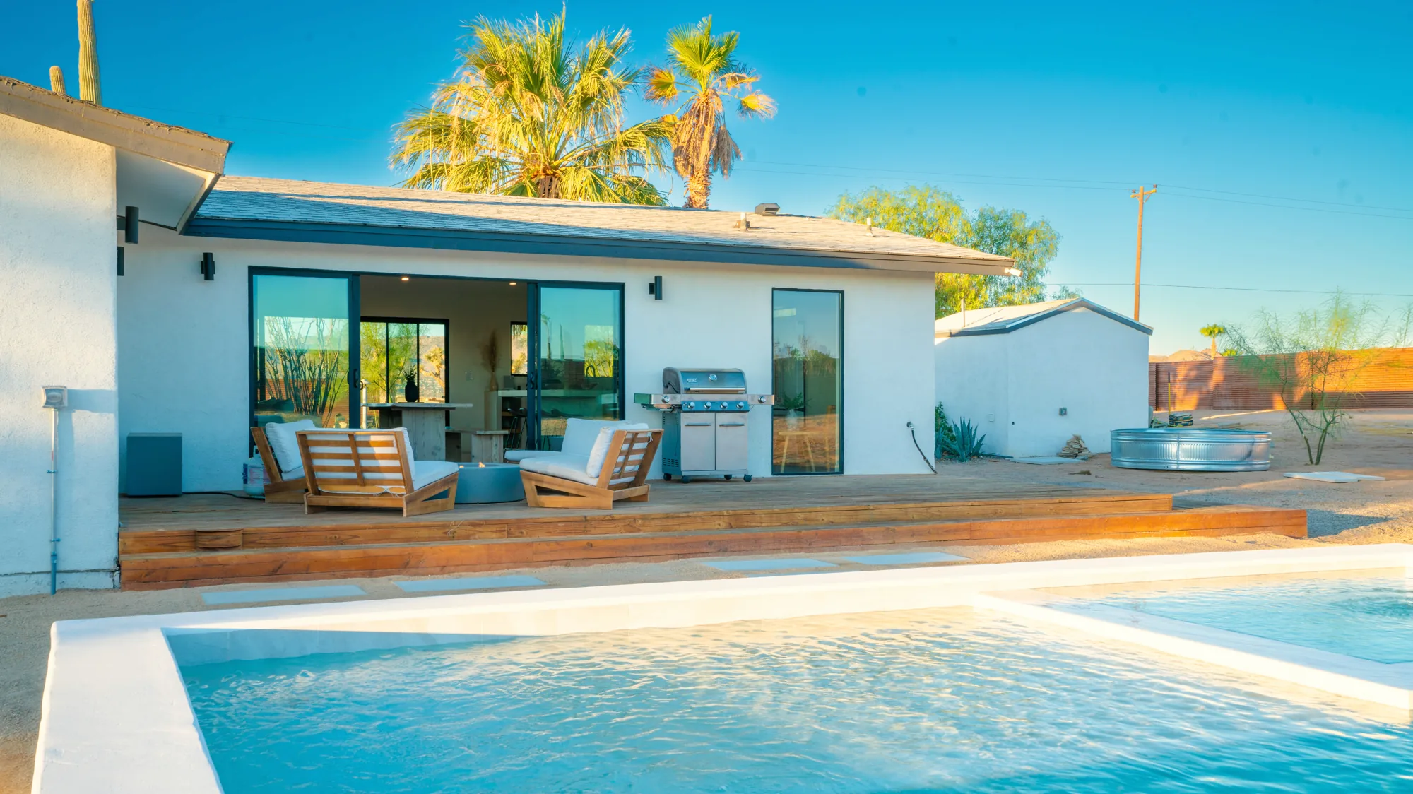 Pool, shaded deck, and hot tub with palms overhead